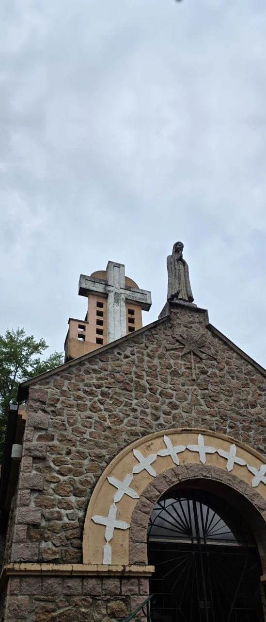 Chapelle Notre‑Dame de Fatima en pierre rose, statue de la Vierge sur le pignon, croix percée.